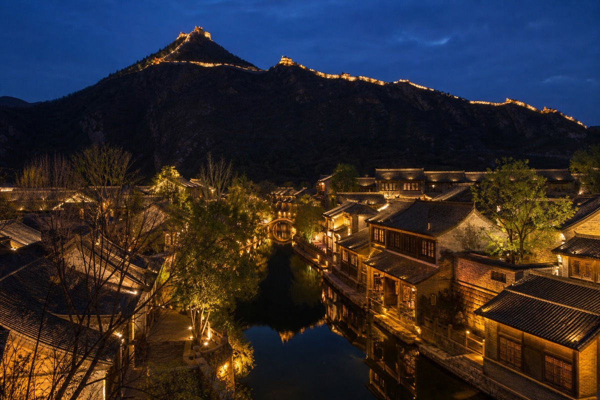 Gubei Water Town lit up at night beneath one of the beautiful sections of the Great Wall at Simatai